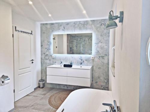 a white bathroom with a sink and a mirror at FeelGood 212 qm Ferienhaus mit 2 Apartments - Garten, Grill & Sauna! in Schauenburg