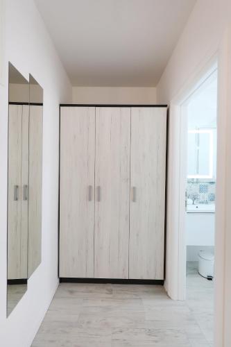 a bathroom with wooden wardrobes in a white room at Piccola Pyrotima in Zadar