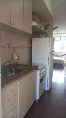 a kitchen with a white refrigerator and a sink at Boulevard center in Guarujá