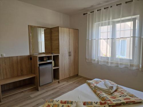 a bedroom with a bed and a cabinet and a window at Apartment and Rooms Amenka in Novalja