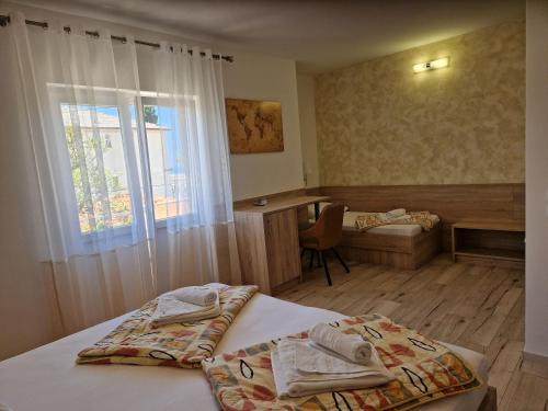a bedroom with a bed and a desk and a window at Apartment and Rooms Amenka in Novalja
