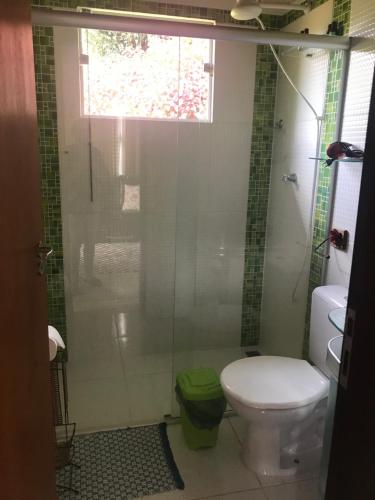 a bathroom with a toilet and a glass shower at Chalés lá na roça in Costas