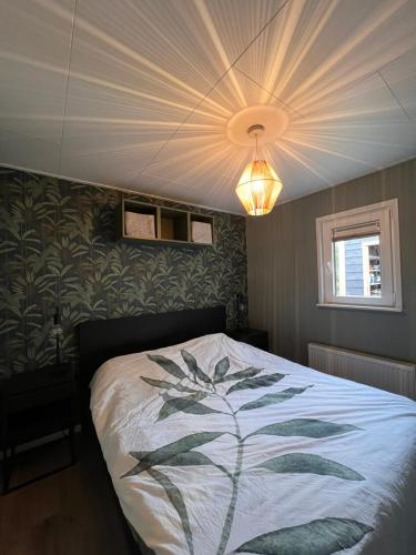 Un dormitorio con una cama con un diseño de hojas. en 4 tot 8 persoons huisje - Veluwemeer - Biddinghuizen - Harderwijk - Elburg en Biddinghuizen