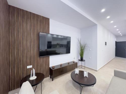 a living room with two tables and a tv on a wall at AleNi City Apartment 1 in Rhodes Town