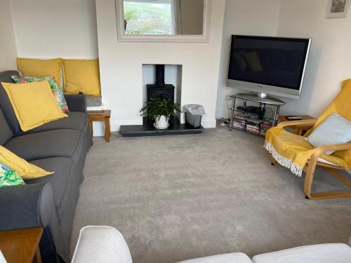 a living room with a couch and a flat screen tv at Linton Luxury Holiday Home in Mevagissey