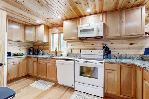 a kitchen with white appliances and wooden cabinets at Log Cabin Life in Arkdale