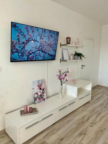 a white living room with a tv on a wall at Magnolia Studio Apartment in Trnávka