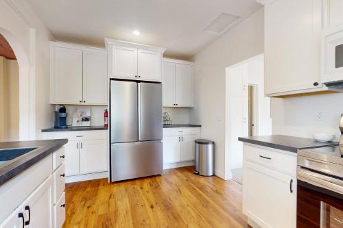 a kitchen with white cabinets and a stainless steel refrigerator at Fountain District Bungalow in Bellingham