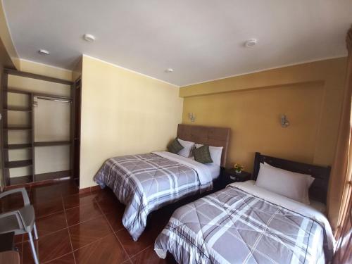 a hotel room with two beds in a room at Hospedaje "LOS QUETZALES DE OXAPAMPA" in Oxapampa