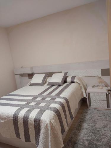 una camera da letto con un grande letto con una coperta a righe di CasaLuaces a Ribadeo