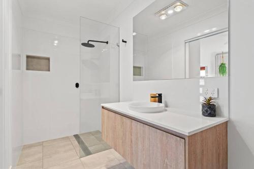 a white bathroom with a sink and a shower at Valley Way in Lennox Head