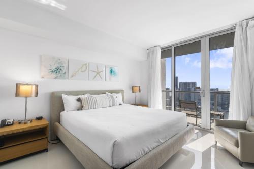 a white bedroom with a large bed and a window at Spectacular Balcony View Retreat Resort Amenities in Hallandale Beach