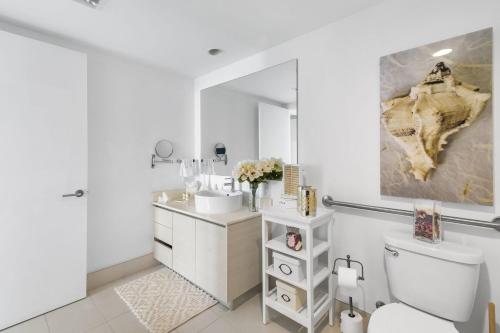 a bathroom with a toilet and a sink and a mirror at Spectacular Balcony View Retreat Resort Amenities in Hallandale Beach