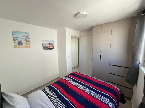 een slaapkamer met een bed met een rood en blauw gestreepte deken bij Casa V25 in Querétaro