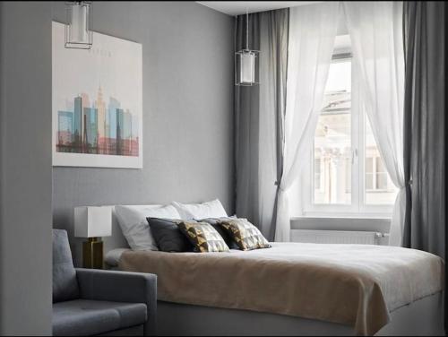 1 dormitorio con cama, ventana y silla en Nowy Świat 60 - 170 m do metra - Prywatne mieszkanie w centrum Warszawy - Better Rental, en Varsovia