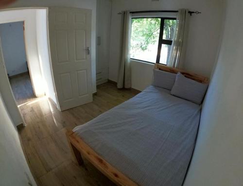 1 dormitorio con 1 cama en una habitación con ventana en A nice bungalow in Sexaxa., en Mirapene