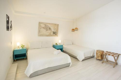 2 camas en una habitación con paredes blancas y mesas azules en Hotel Barahona Cartagena, en Cartagena de Indias
