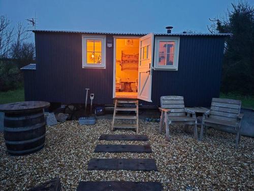 a tiny house with a ladder and two chairs at Shepherds haven hut Near Padstow in Saint Issey