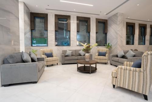a lobby with couches and a table and windows at Rawha Al Maqam Ajyad Hotel in Makkah