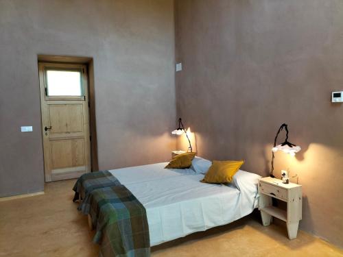 a bedroom with a bed with two lamps on it at Mas la Llum, la casa de palla in Arens de Lledó