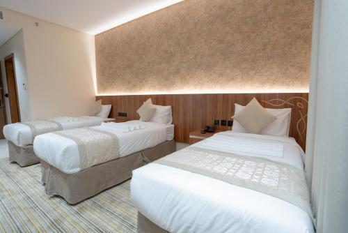 a hotel room with two beds with white sheets at Rawha Al Maqam Ajyad Hotel in Makkah
