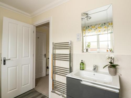 Baño blanco con lavabo y espejo en Coral House, en Cromer