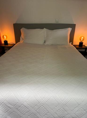 a large bed with white sheets and pillows at Romeu in Quarteira
