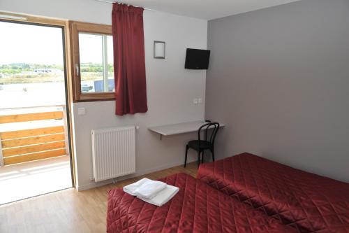 a room with a bed and a desk and a window at Relais de Barbezieux in Barbezieux