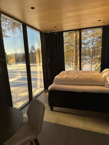 Schlafzimmer mit einem Bett und großen Fenstern in der Unterkunft Spegle Hyllandsfoss in Åmot