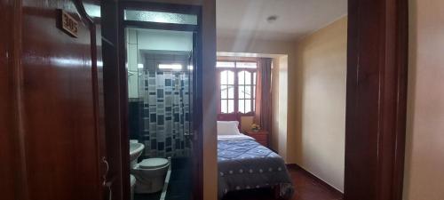 a bedroom with a bed and a glass shower door at Hospedaje "LOS QUETZALES DE OXAPAMPA" in Oxapampa