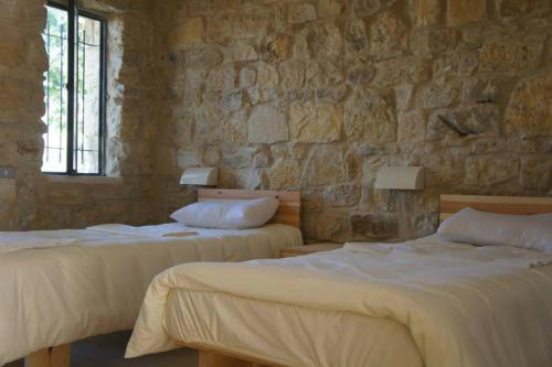 two beds in a room with a stone wall at Dana Hotel in Tufailah