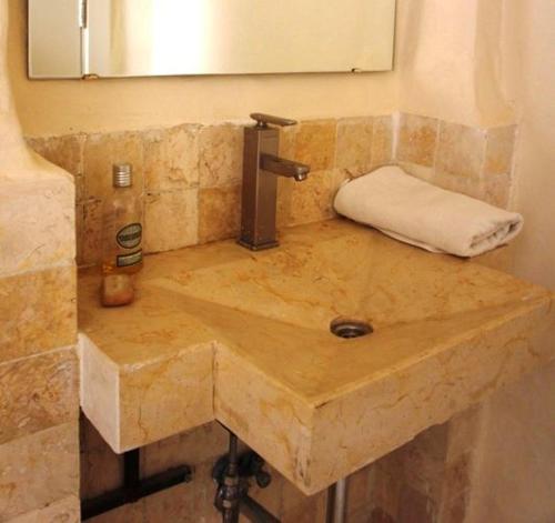 lavabo de piedra en el baño con espejo en Dana Hotel en Tufailah
