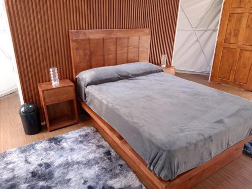 a bedroom with a bed with a wooden headboard and a rug at Glamping Don Delfis in Valle de Bravo