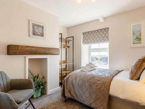 a bedroom with a bed and a chair and a window at Bells Cottage - 5 min walking distance to train station and town on your doorsteps in St Austell
