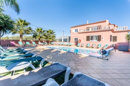 uma piscina com espreguiçadeiras e um edifício em Villa Paradis Pêra - Casa completa para férias em Pêra