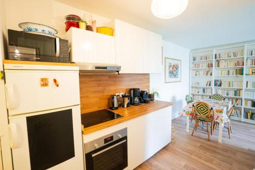 une cuisine avec des armoires blanches et un comptoir dans l'établissement Jolie nid familiale, à Paris