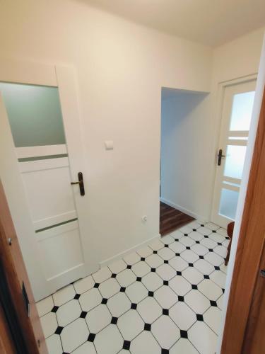 a white bathroom with a black and white tiled floor at Apartament Inka in Gollnow