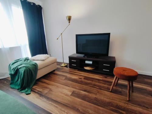 a living room with a television and a chair at Apartament Inka in Gollnow