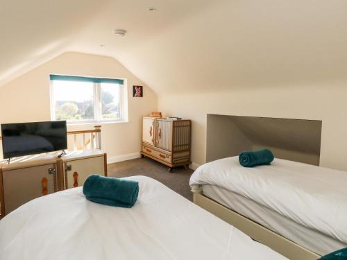a bedroom with two beds and a tv and a window at The Chocolate Box in Weymouth