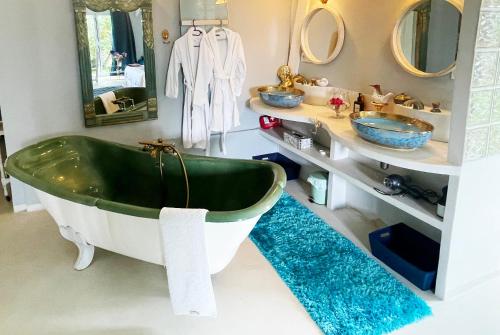 y baño con bañera verde y 2 lavabos. en Suite Loft de la Sirène Grande piscine privée, en Marais-Vernier