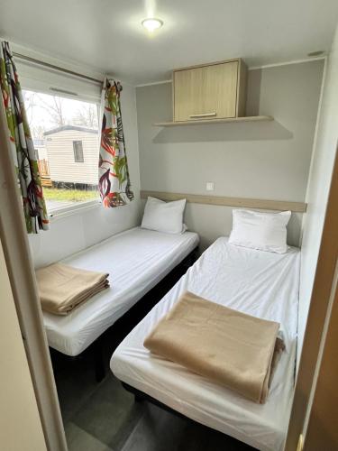 two beds in a small room with a window at La cabane du lac in Aureilhan