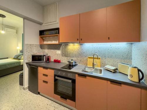 La cuisine est équipée d'armoires orange et d'un four avec plaques de cuisson. dans l'établissement Luxury Studio with Panoramic Views, à Athènes