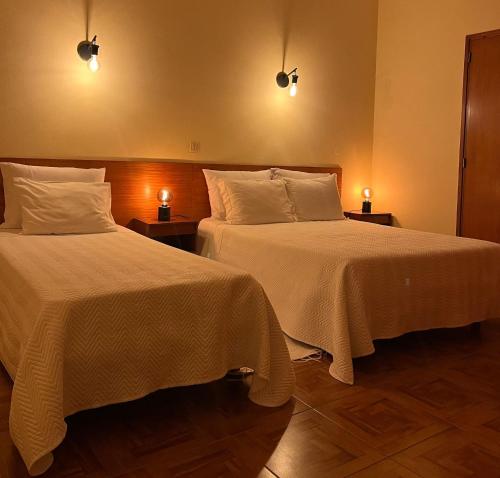 two beds in a hotel room with two lamps at Romeu in Quarteira