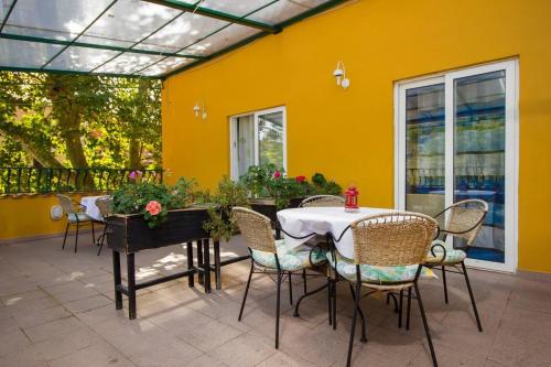 a patio with a table and chairs and a yellow wall at Apartments and Rooms Villa Marija in Skradin