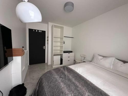 - une chambre avec un lit blanc et une porte noire dans l'établissement Appartement au pied du Stade de France, à Saint-Denis
