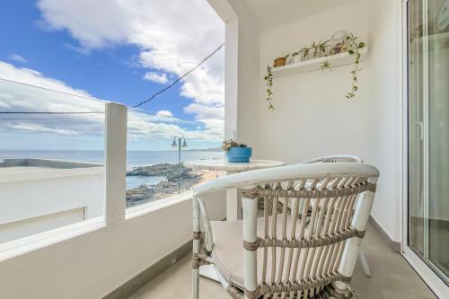 een witte stoel op een balkon met uitzicht op de oceaan bij Casa Burgao n5 on the front line with seaview terrace in Punta de Mujeres