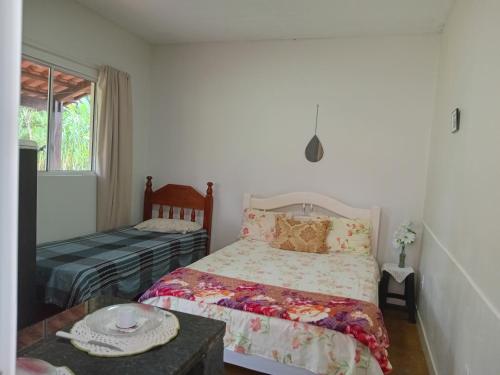 1 dormitorio con cama, mesa y ventana en Recanto São Francisco de Assis en Pirenópolis