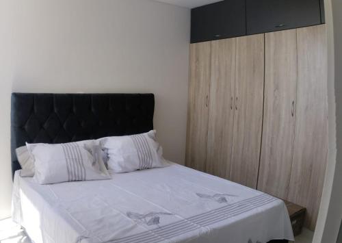 a bedroom with a large bed with a black headboard at Encantador apartamento con aire in Neiva