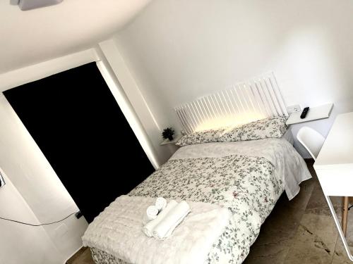 a small bedroom with a bed with white sheets at Alojamiento Bruckner in Málaga