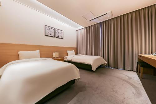 a hotel room with two beds and a desk at Sejong City Osong Hotel in Cheongju